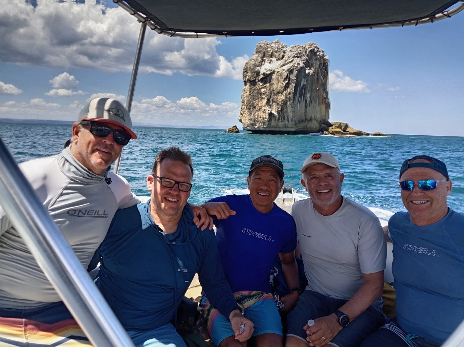 A Boos Adventures crew on the boat with Roca Bruja behind them